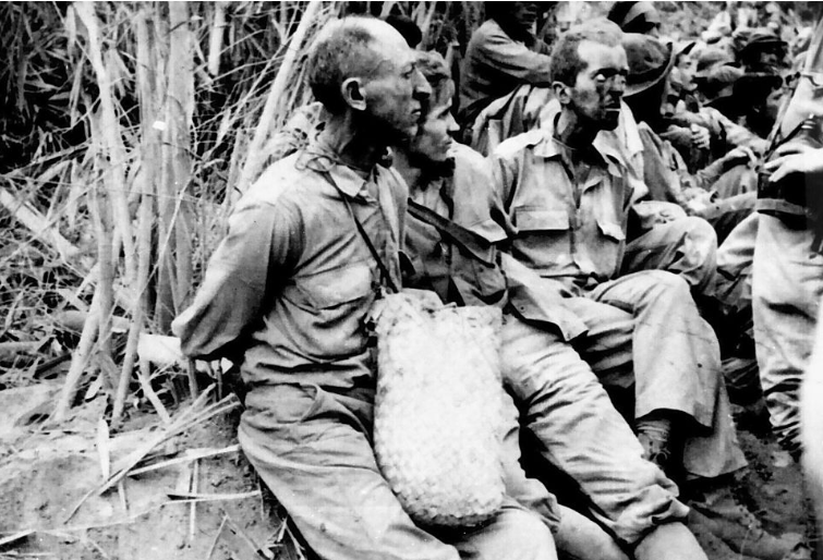 American and Filipino soldiers are marched by Japanese guards to prison camps following the surrender of the Bataan Peninsula in April 1942.